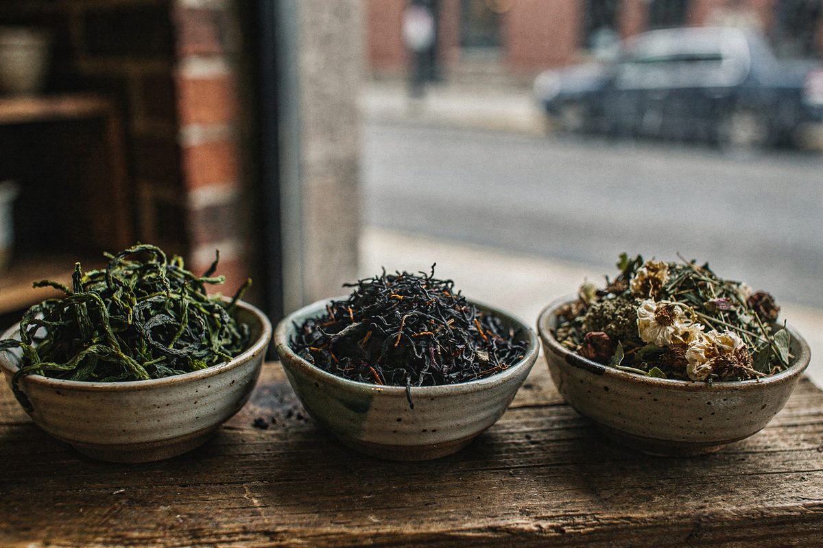 Assorted bowls of whole leaf green tea, black tea, and herbal infusions
